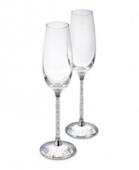 A flurry of sparkling miniature crystals fill the stems of these toasting flutes. Exquisitely crafted by Swarovski, the Austrian leader in crystal artistry for over 100 years, this pair of champagne flutes with embellished bases is cut from solid crystal. 2-3/4 x 10 high.
