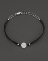 Diamonds, set in a circle of white gold, dazzle on a black leather bracelet. By Meira T.