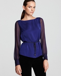 A searing jewel tone glows atop a fluid T Tahari blouse, finished with sheer sleeves and a high/low hem for contemporary edge. Slip the statement silhouette over dark denim for modern polish.
