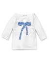 A white boat neck Pearls & Popcorn long sleeve tee features a stripe print bow on the front and delicate Mother of Pearl shoulder button closure.